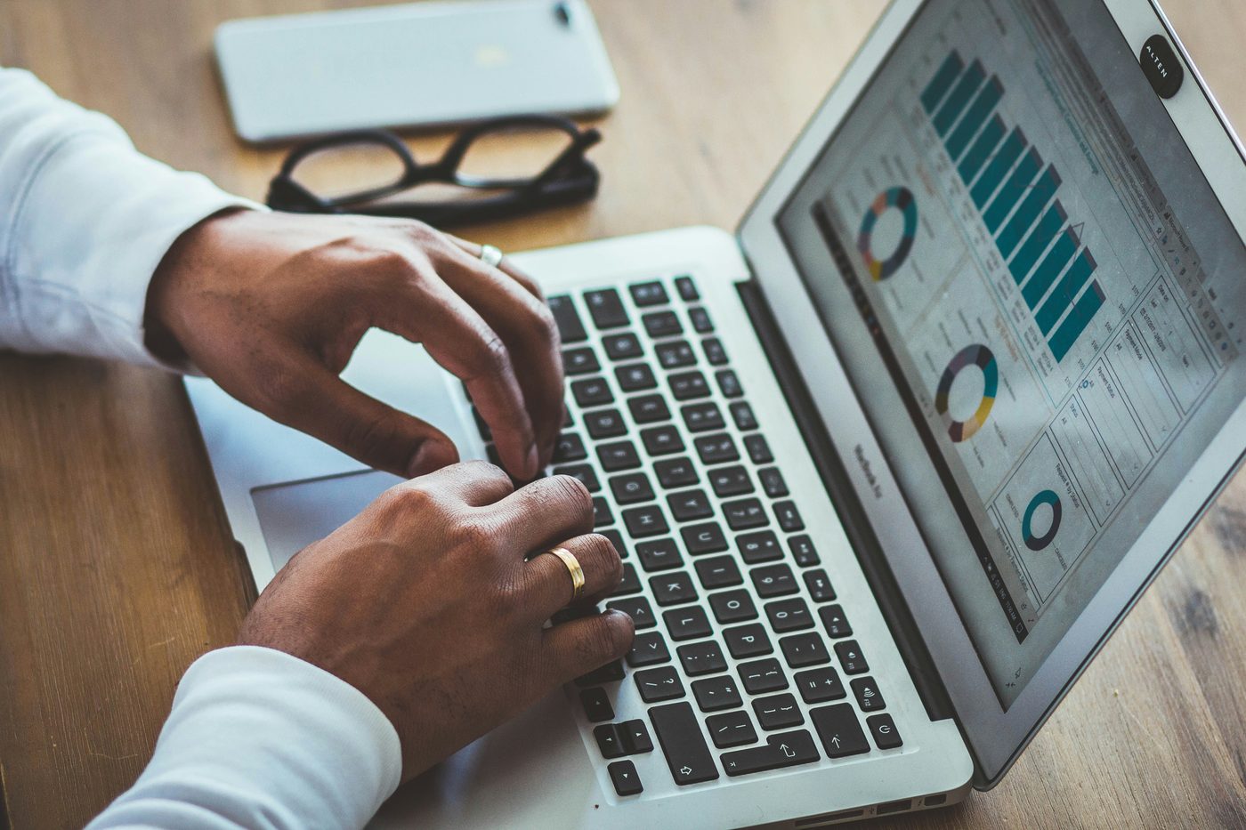 Hands typing on a laptop showing a chart dashboard