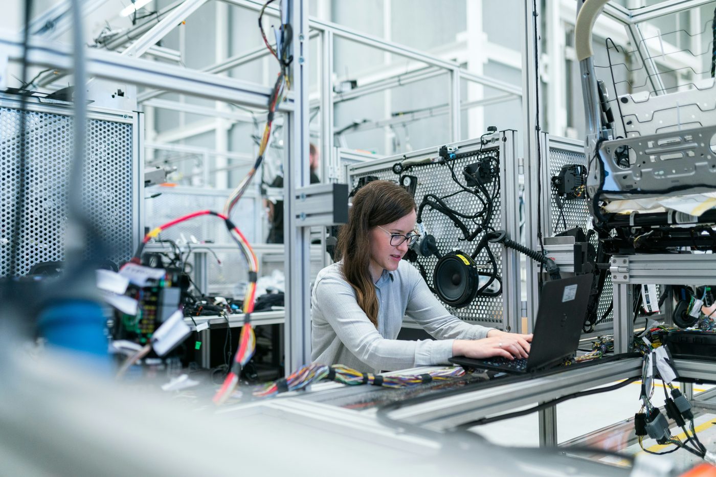 Engineer working on a laptop next to an automotive wiring harness test rig