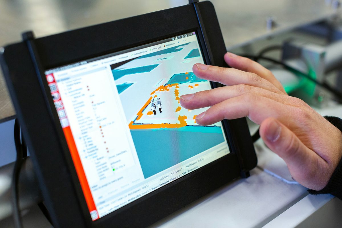 Hand interacting with a robot navigation and mapping interface on a tablet